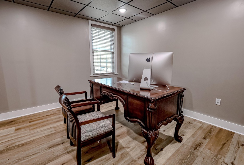 Office space with light wood finished floors, baseboards, and a drop ceiling