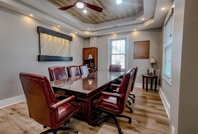 Dining space featuring a tray ceiling, baseboards, light wood-style floors, ceiling fan, and wooden ceiling