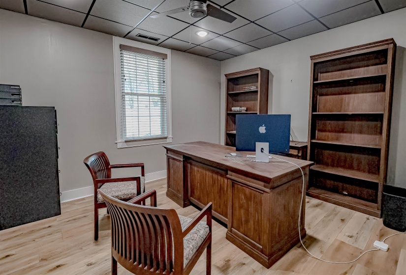 Office space with light wood finished floors, baseboards, a paneled ceiling, and visible vents