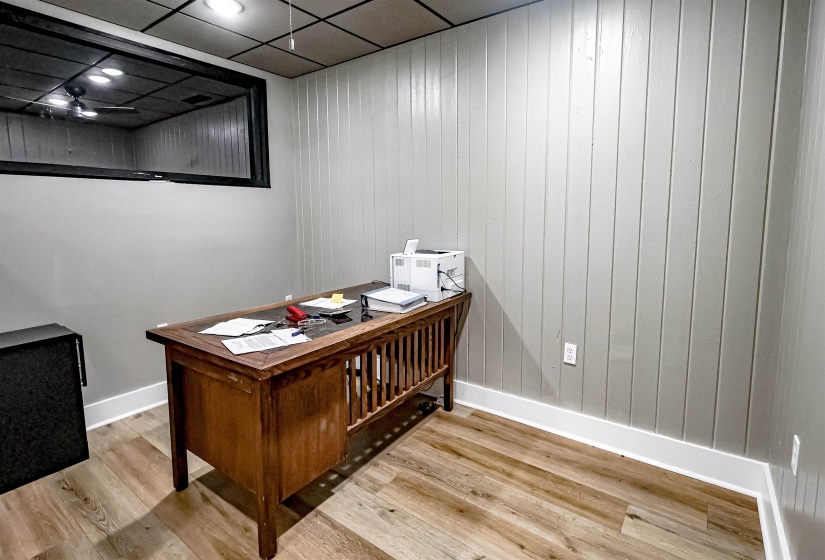 Office with wood finished floors, baseboards, and wooden walls