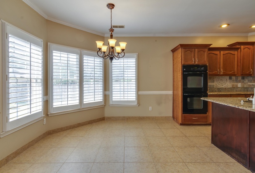 Kitchen featuring decorative light fixtures, backsplash, crown molding, a chandelier, and light stone countertops