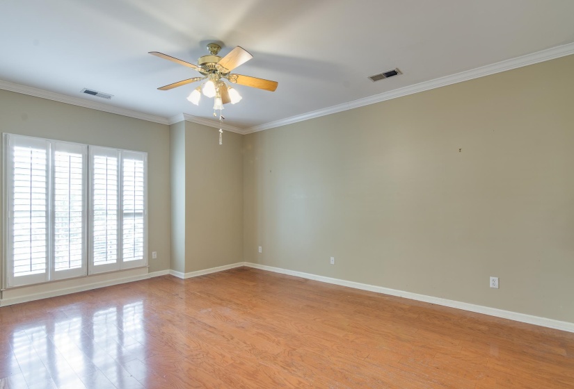 Primary bedroom featuring ornamental molding, light wood finished floors, and ceiling fan