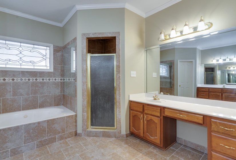 Bathroom with ornamental molding, a shower stall, a garden tub, vanity, and light tile patterned floors
