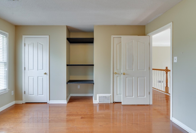 Unfurnished bedroom featuring light wood finished floors, two closets, and multiple windows