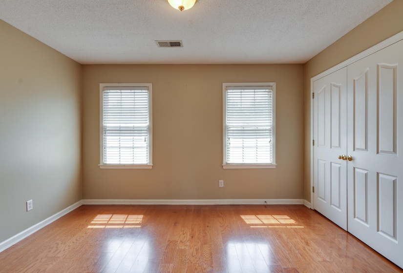 Unfurnished bedroom featuring multiple windows, light wood-style floors, a textured ceiling, and a closet