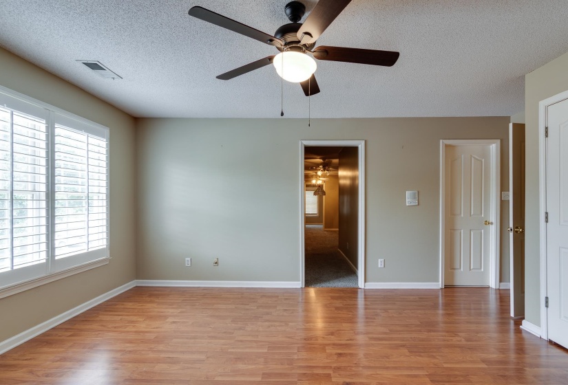 Empty room featuring a textured ceiling, plenty of natural light, light wood-type flooring, and a ceiling fan