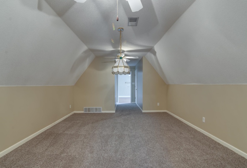 Additional living space featuring a textured ceiling, carpet flooring, ceiling fan, and vaulted ceiling
