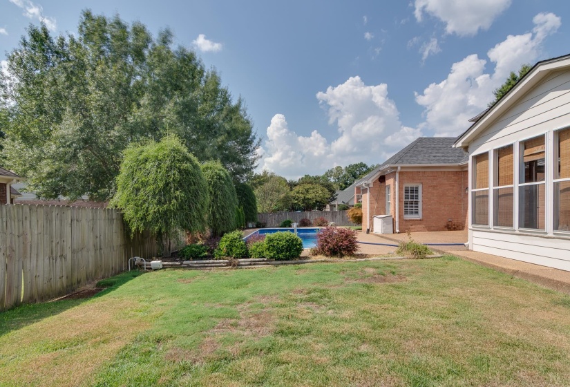 Fenced backyard featuring a sunroom and a patio