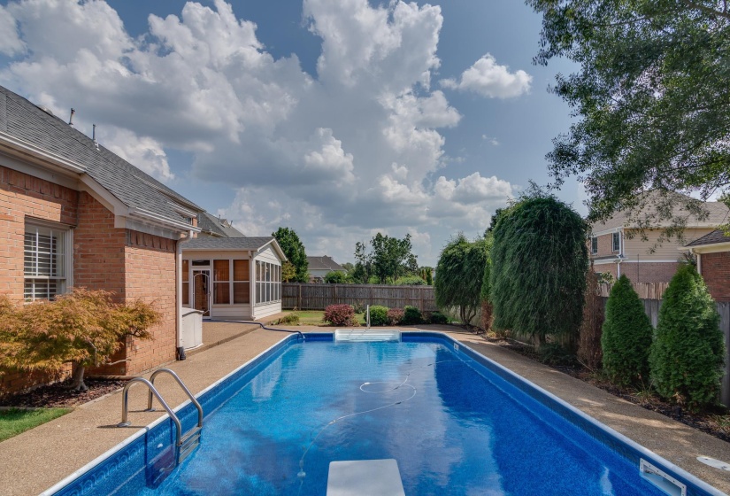View of pool featuring a sunroom, a fenced backyard, a patio area, and a diving board