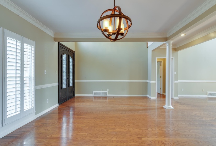 Unfurnished dining area featuring light wood-type flooring, ornamental molding, a chandelier, and ornate columns