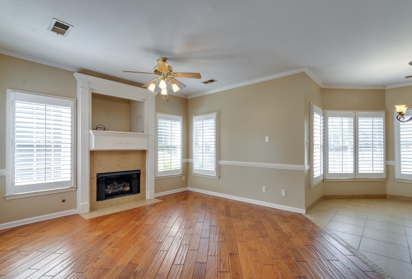 Unfurnished living room with ornamental molding, ceiling fan, light wood-style flooring, a fireplace, and a chandelier