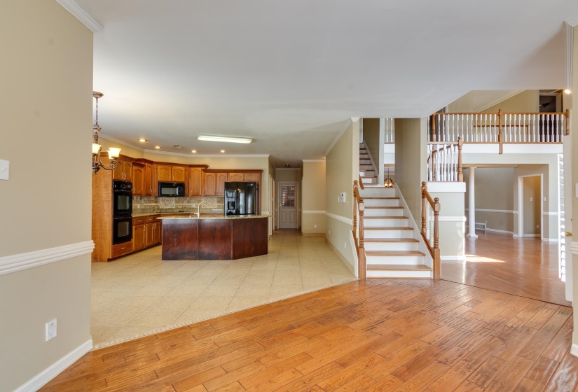 Kitchen with light wood-style flooring, crown molding, open floor plan, a center island with sink, and backsplash
