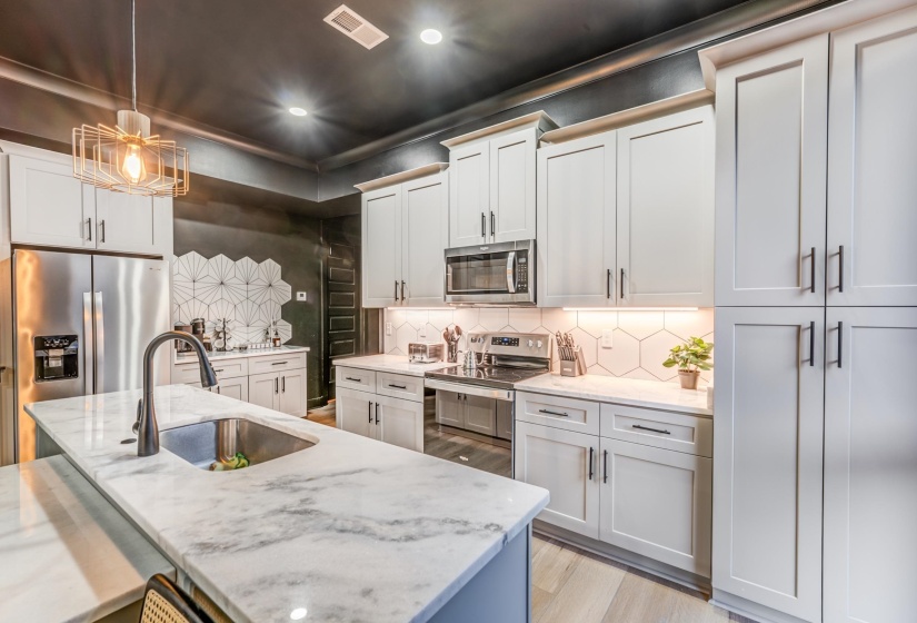 Kitchen featuring stainless steel appliances, a sink, light wood-type flooring, visible vents, and decorative backsplash