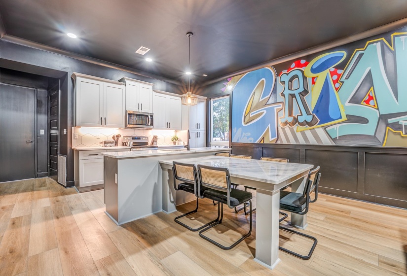 Kitchen featuring white cabinets, appliances with stainless steel finishes, tasteful backsplash, and light wood finished floors
