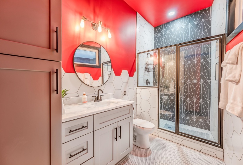 Bathroom featuring a shower stall, tile patterned floors, vanity, tile walls, and toilet