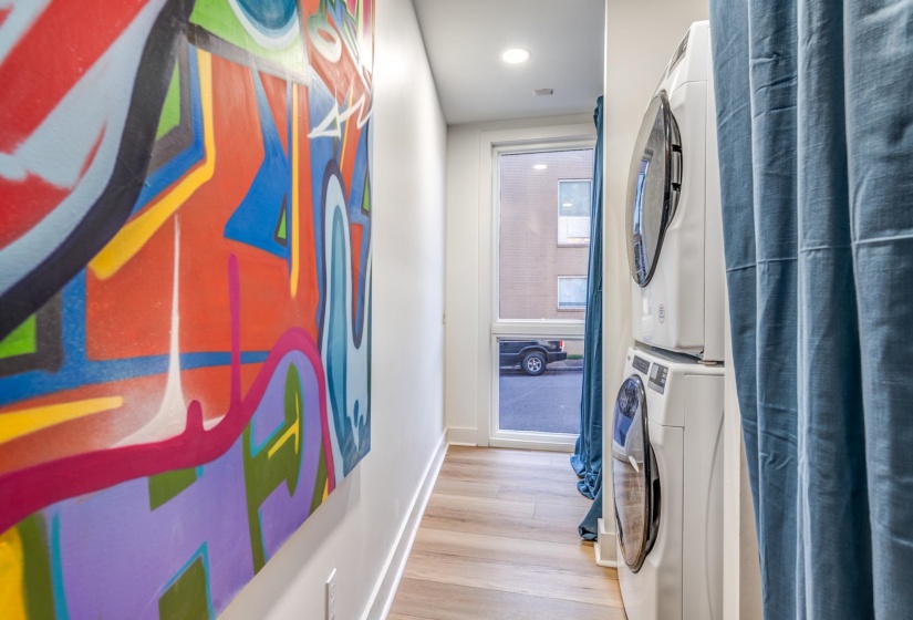 Clothes washing area with wood finished floors, stacked washer / drying machine, baseboards, laundry area, and recessed lighting