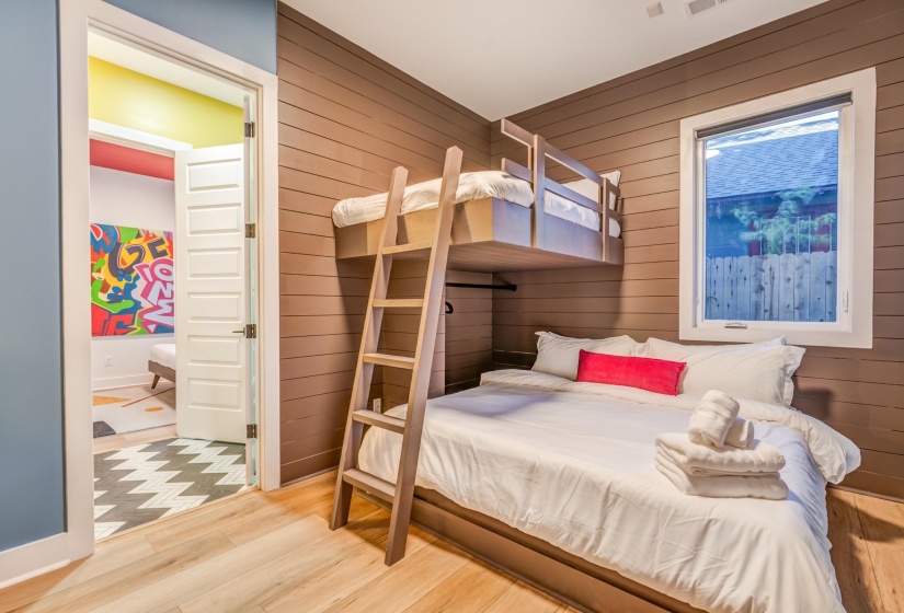 Bedroom with visible vents, baseboards, wood finished floors, and wood walls