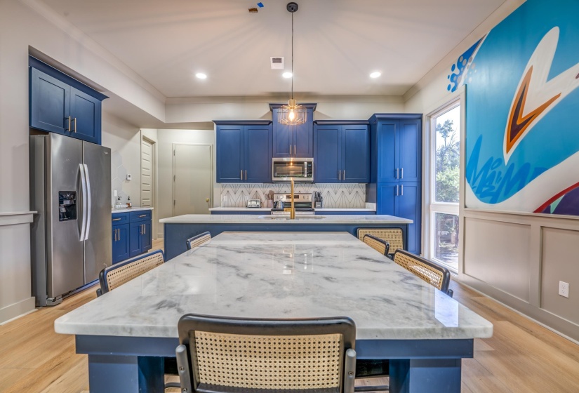 Kitchen with a kitchen breakfast bar, tasteful backsplash, an island with sink, blue cabinetry, and appliances with stainless steel finishes