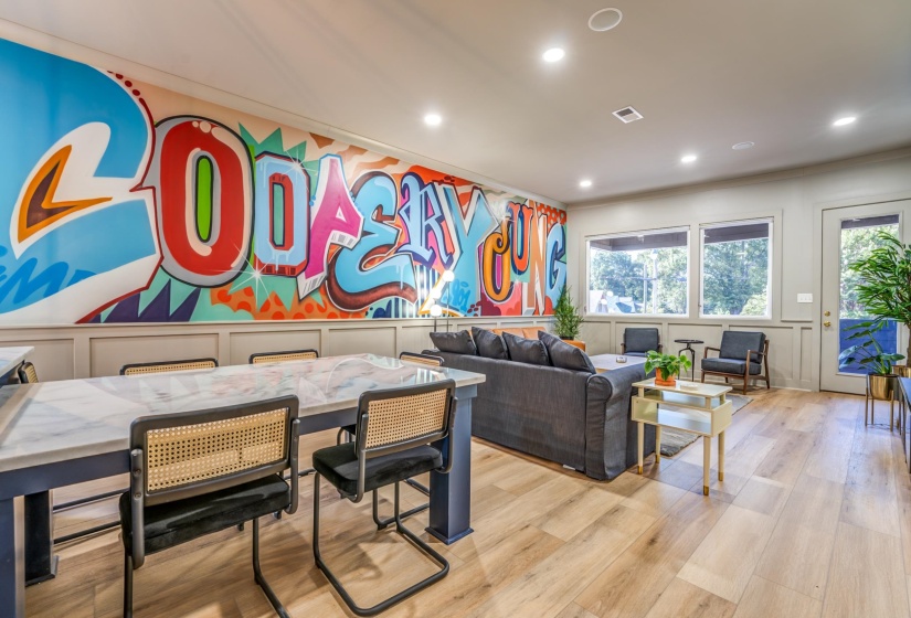 Living room with recessed lighting, wood finished floors, a decorative wall, and ornamental molding