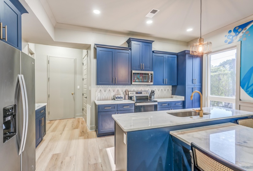 Kitchen with blue cabinets, stainless steel appliances, light wood-style flooring, and a sink