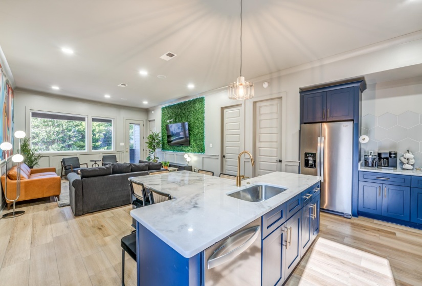 Kitchen featuring blue cabinets, a center island with sink, stainless steel appliances, and a sink