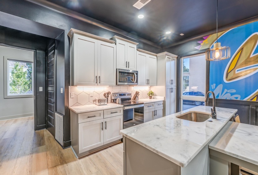Kitchen with light wood-type flooring, stainless steel appliances, a sink, and tasteful backsplash