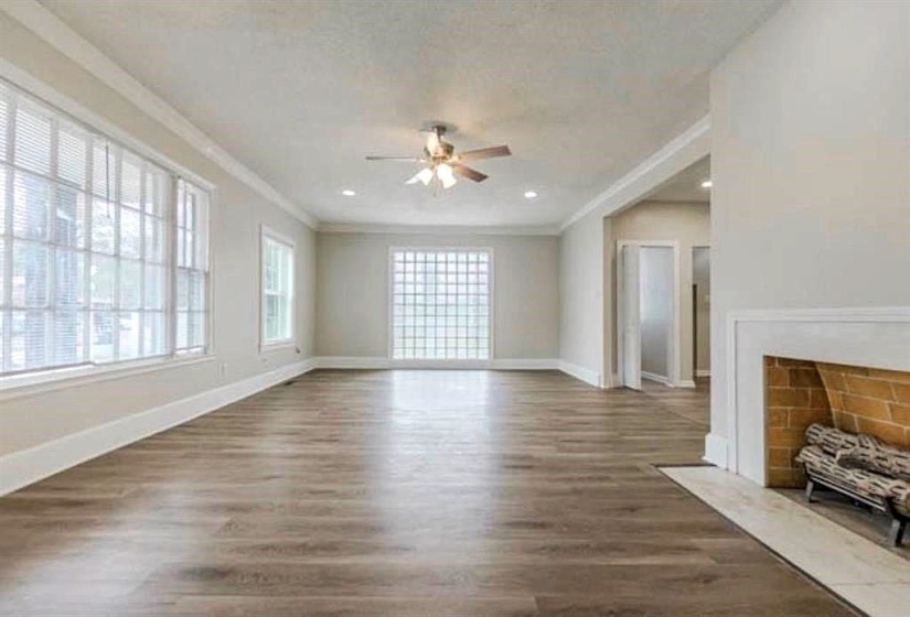Unfurnished living room with crown molding, ceiling fan, and dark hardwood / wood-style floors