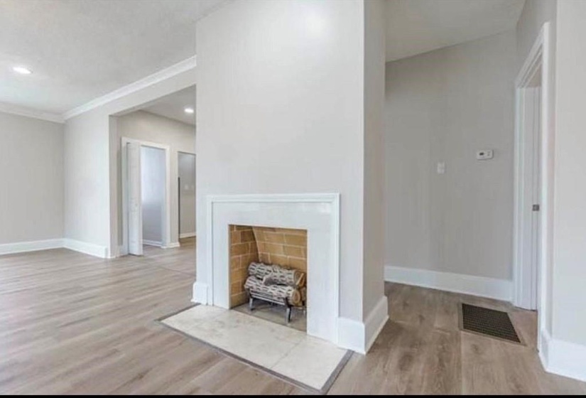 Unfurnished living room featuring ornamental molding and light hardwood / wood-style floors