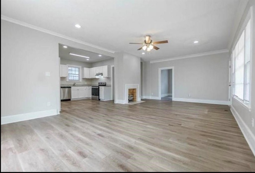 Unfurnished living room featuring ornamental molding, light hardwood / wood-style flooring, and ceiling fan