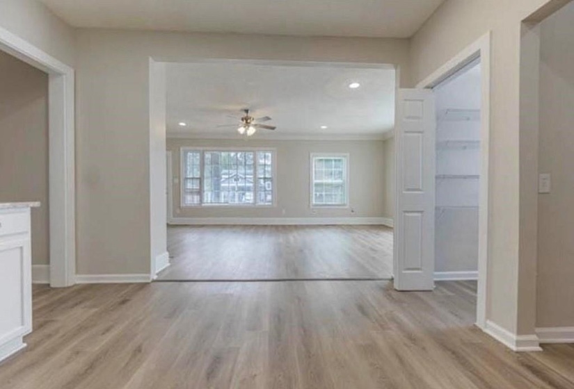 Unfurnished living room with ceiling fan, light hardwood / wood-style flooring, and ornamental molding
