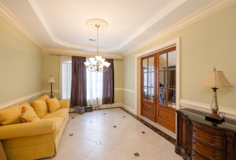 Entrance foyer featuring french doors, plenty of natural light, a chandelier, a tray ceiling, and crown molding