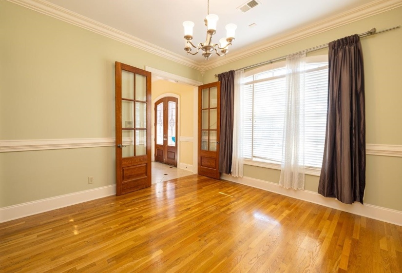 Empty room with light wood-type flooring, french doors, visible vents, and an inviting chandelier