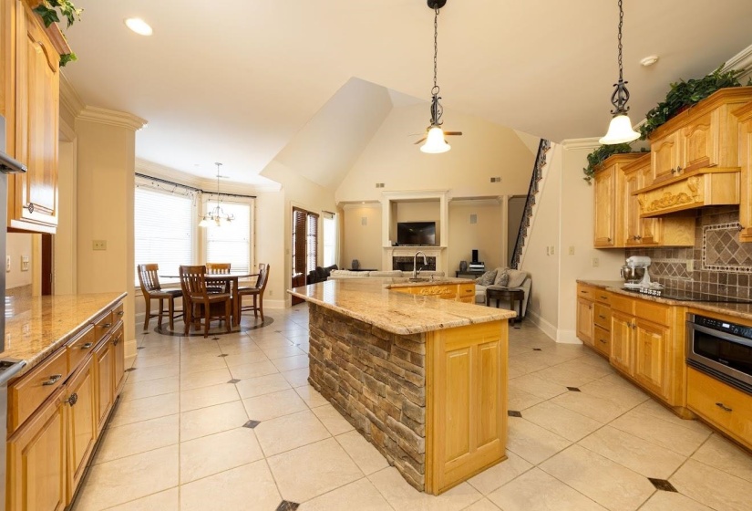 Kitchen featuring light tile patterned flooring, tasteful backsplash, stainless steel oven, and open floor plan