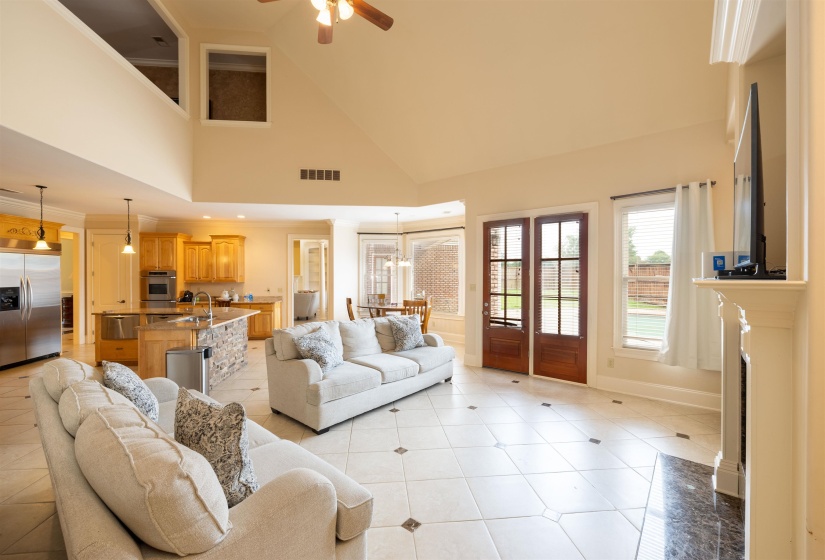 Heart area with a towering ceiling, light tile patterned flooring, and ceiling fan