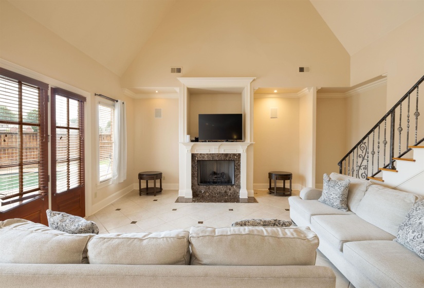 Hearth room featuring high vaulted ceiling, light tile patterned floors, a fireplace, and stairway