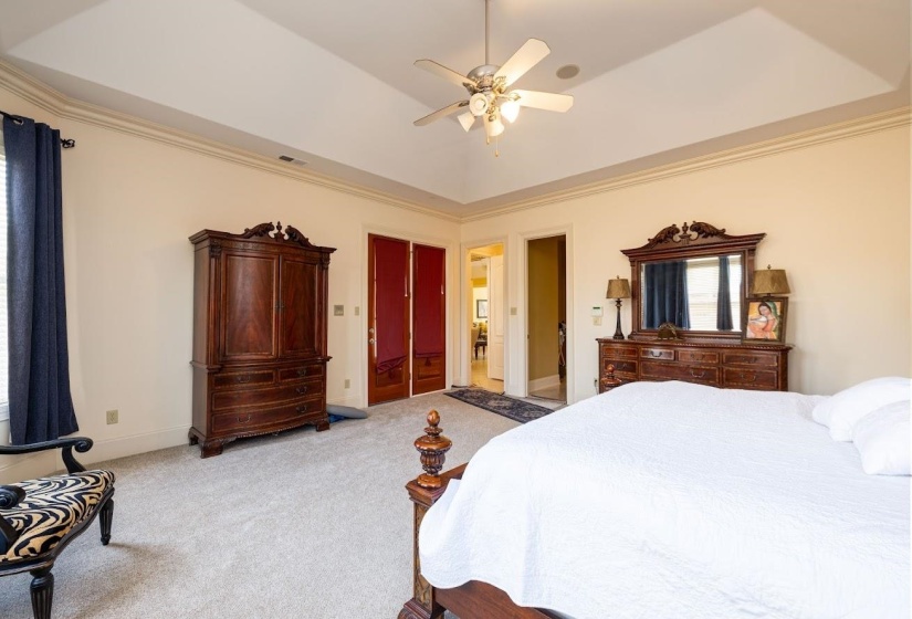 Bedroom with crown molding, visible vents, a ceiling fan, and light colored carpet