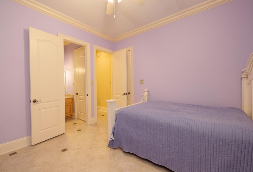 Bedroom featuring ornamental molding, ensuite bathroom, light tile patterned floors, and ceiling fan