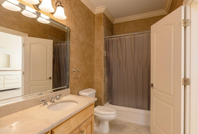 Bathroom with tile patterned flooring, shower / bath combination with curtain, toilet, vanity, and crown molding