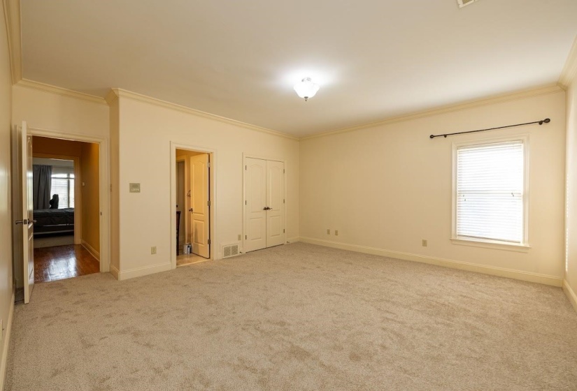 Unfurnished bedroom featuring carpet floors, ornamental molding, visible vents, and baseboards