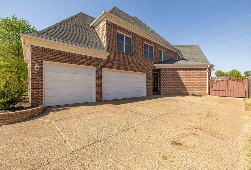 View of front facade featuring a gate, brick siding, driveway, a garage, and roof with shingles