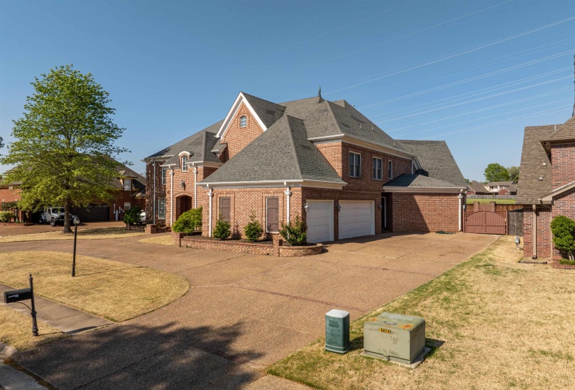 Traditional-style house with a gate, concrete driveway, a shingled roof, a garage, and brick siding