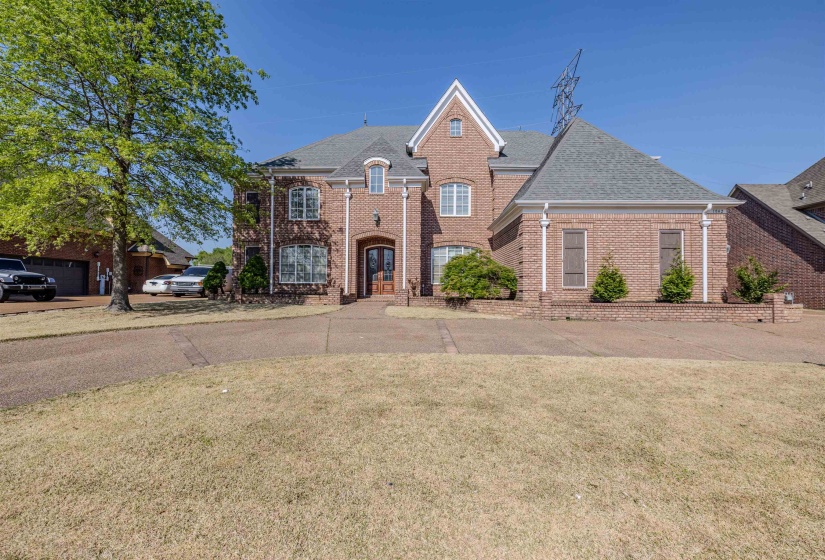 View of front of house with a shingled roof, a front lawn, and brick siding