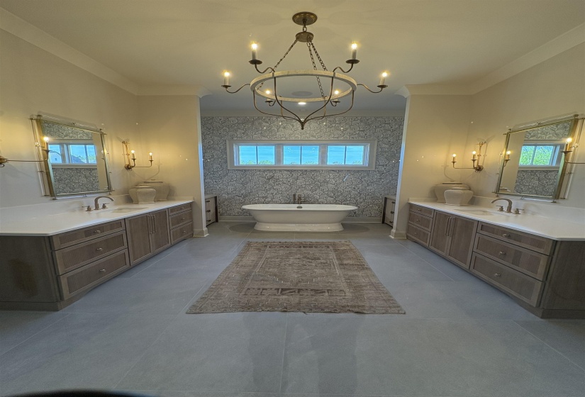 Bathroom with two vanities, a freestanding tub, a notable chandelier, and a sink