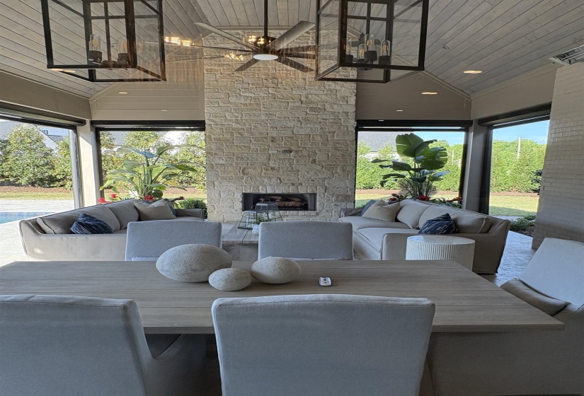Dining area with an outdoor stone fireplace, a ceiling fan, and plenty of natural light