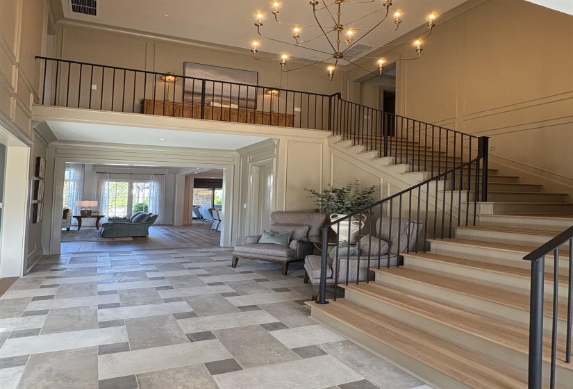 Foyer featuring visible vents, a high ceiling, stairway, and a decorative wall