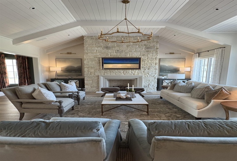 Living room with wooden ceiling, a stone fireplace, and vaulted ceiling with beams