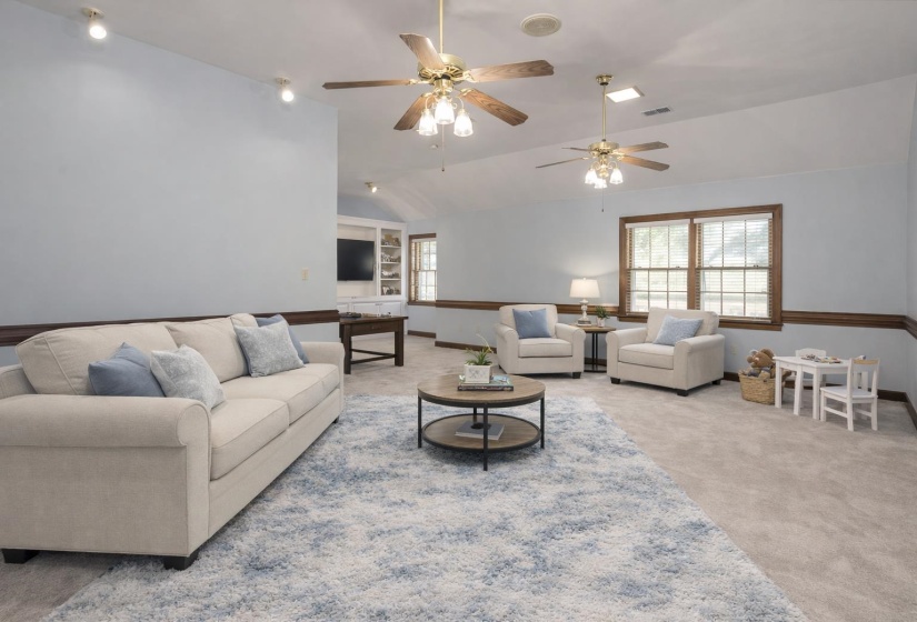 Living room featuring light colored carpet, built in features, vaulted ceiling, and ceiling fan