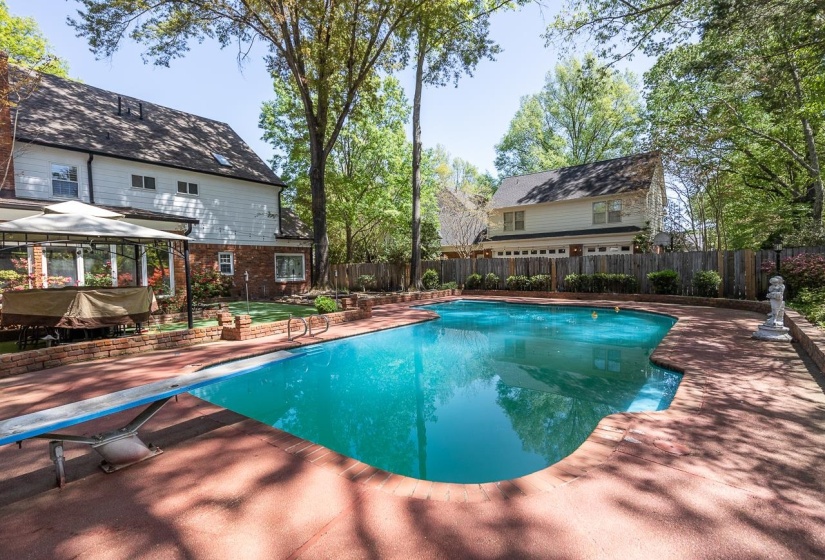 View of pool with a fenced backyard, a diving board, and patio surround