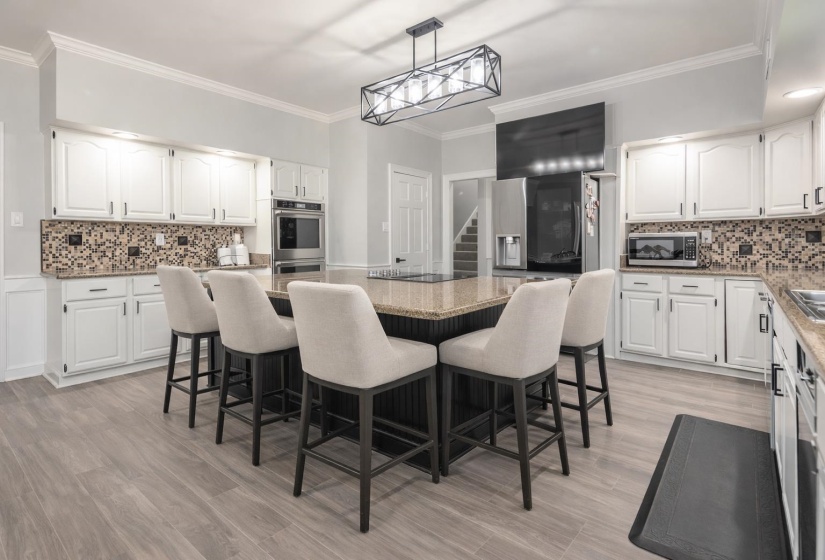 Kitchen featuring decorative backsplash, a kitchen island, ornamental molding, light stone countertops, and a kitchen breakfast bar