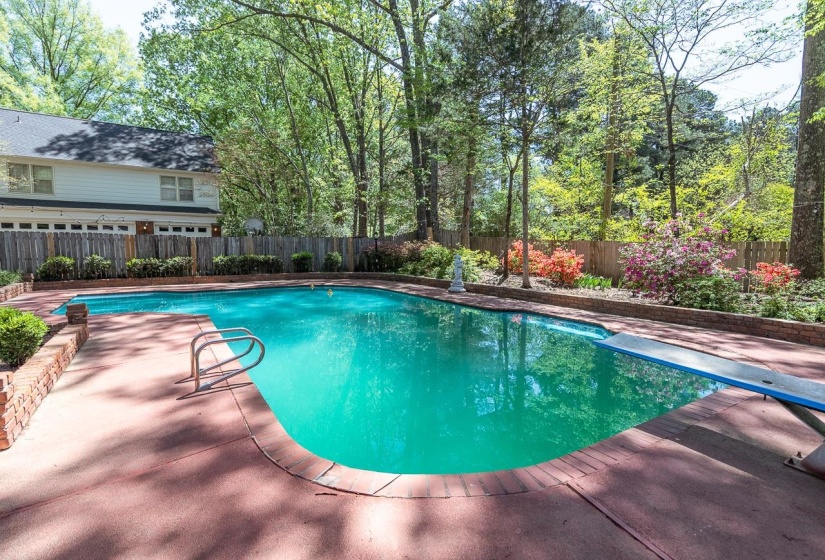 View of swimming pool with a fenced backyard, a diving board, and patio surround